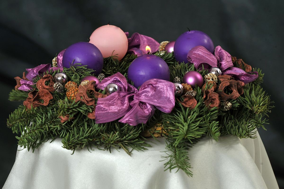 Adventskranz mit drei violetten Kerzen und einer rosafarbenen Kerze